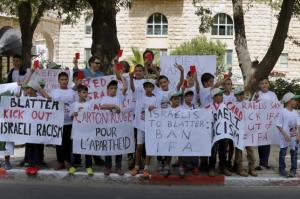 Palestinian children hold up red cards during a protest during the arrival of FIFA president Blatter to his Jerusalem hotel on May 19. (Credit: Reuters/Ammar Awad)